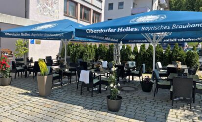 Unser Biergarten mit Tischen, Stühlen, dekoriert mit hübschen Pflanzen, unter großen Sonnenschirmen - hier verweilt man gerne!©Özay_Kül