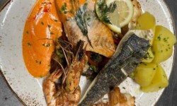 Fischteller Rusticana - Dorade, Lachs und Garnelen auf marktfrischem Gemüse, in Hummersauce, dazu Salzkartoffeln©Özay_Kül